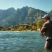 Cast with the Best fly fishing rods to catch fish in a serene river surrounded by mountains.
